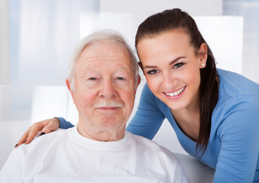 Portrait of young female caretaker with senior man at nursing home